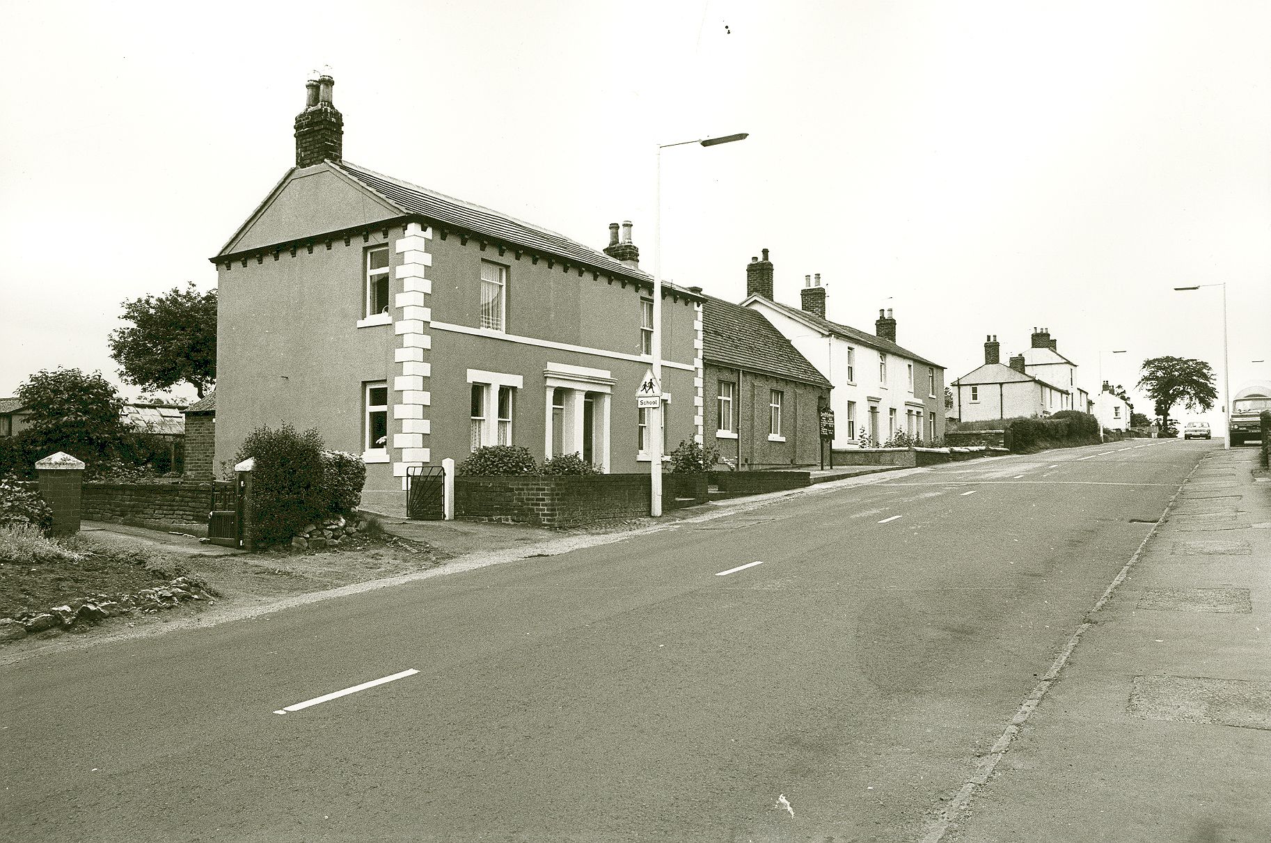 A black-and-white photograph looking up Moorhouse Road, showing terraced houses and a school crossing sign