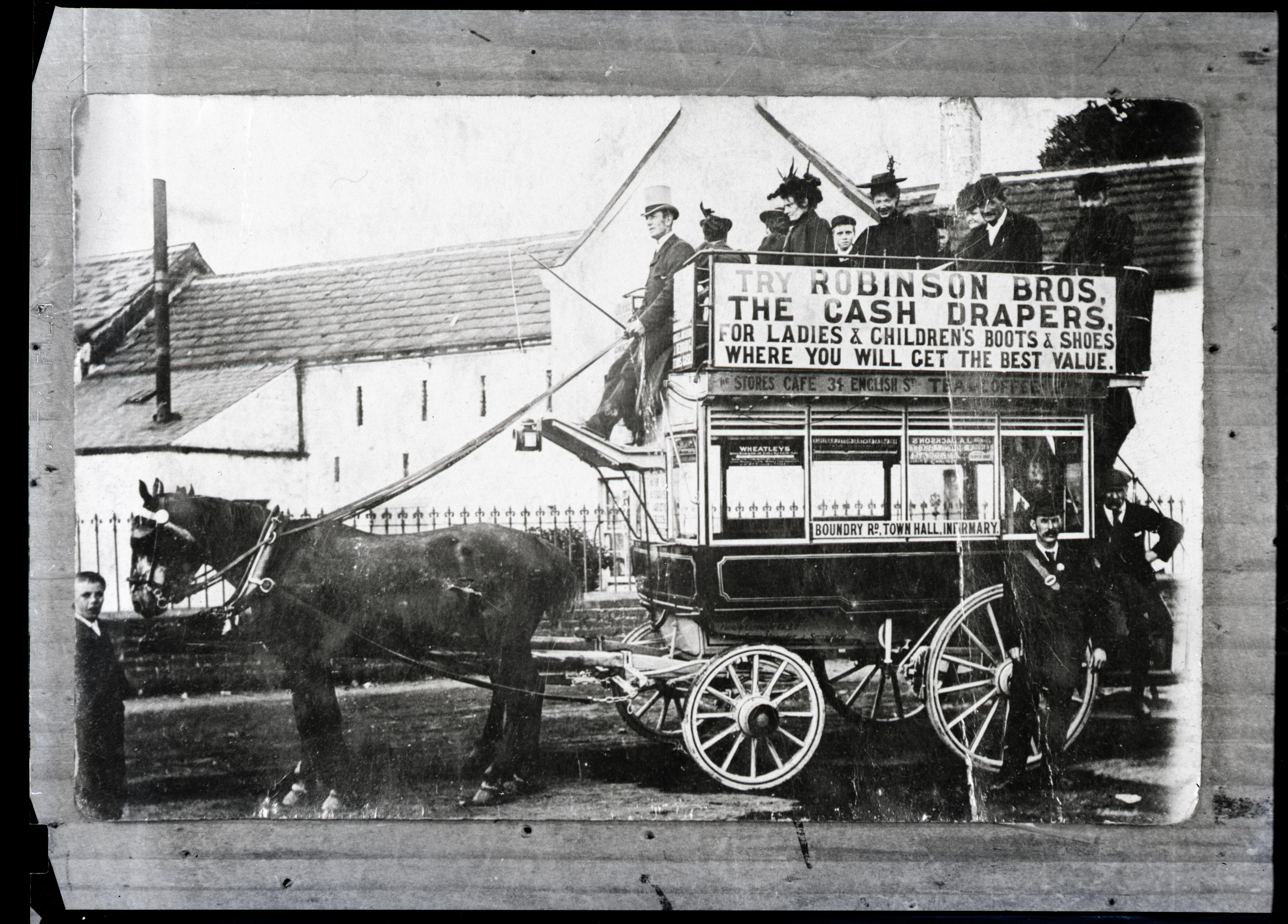 A Victorian horse-drawn omnibus on Newtown Road, with passengers on the open upper deck and a Robinson Bros drapers advertisement on the side